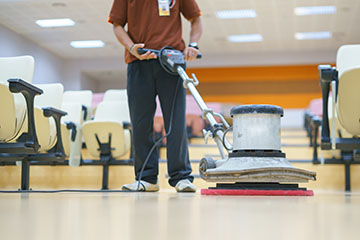 Asian worker cleaning ground surface using floor scrubber machine